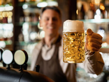 Close-up of bartender holding a glass of beer in a pub.